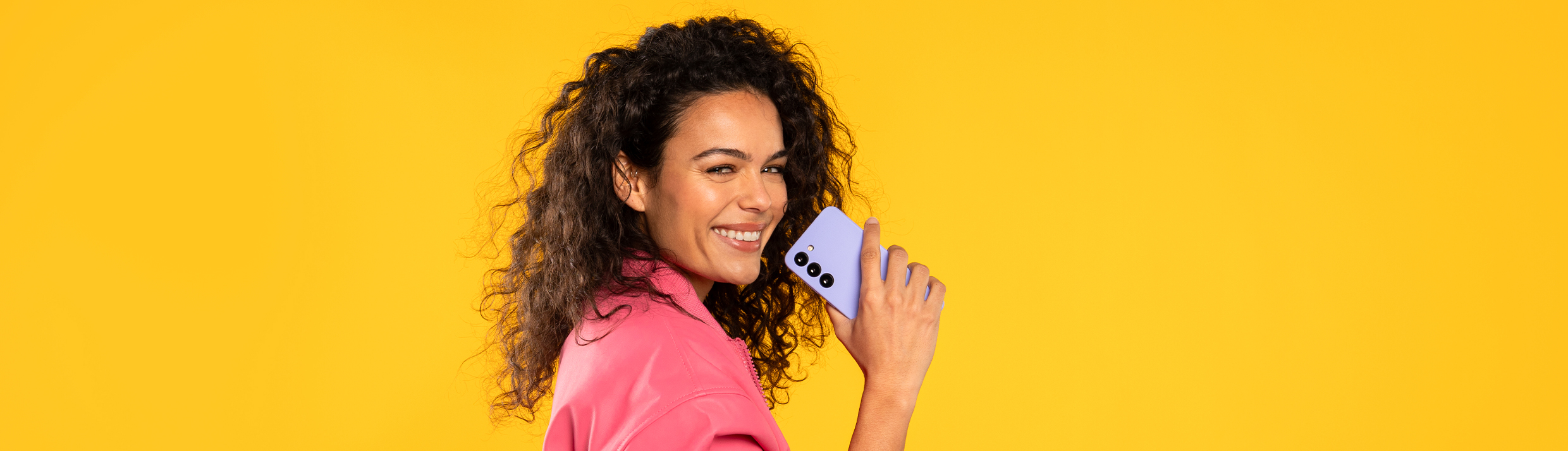 Eine Frau hält lachend eine lila Handyhülle, der Hintergrund ist gelb.