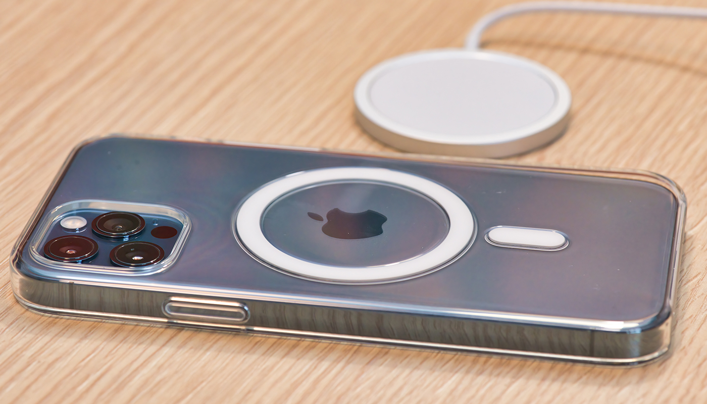 iPhone 12 Pro mit MagSafe-Hülle und Lader auf Holztisch.