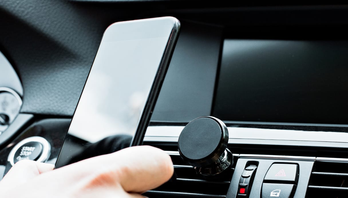Jemand im Auto hält ein Telefon mit Halterungen.