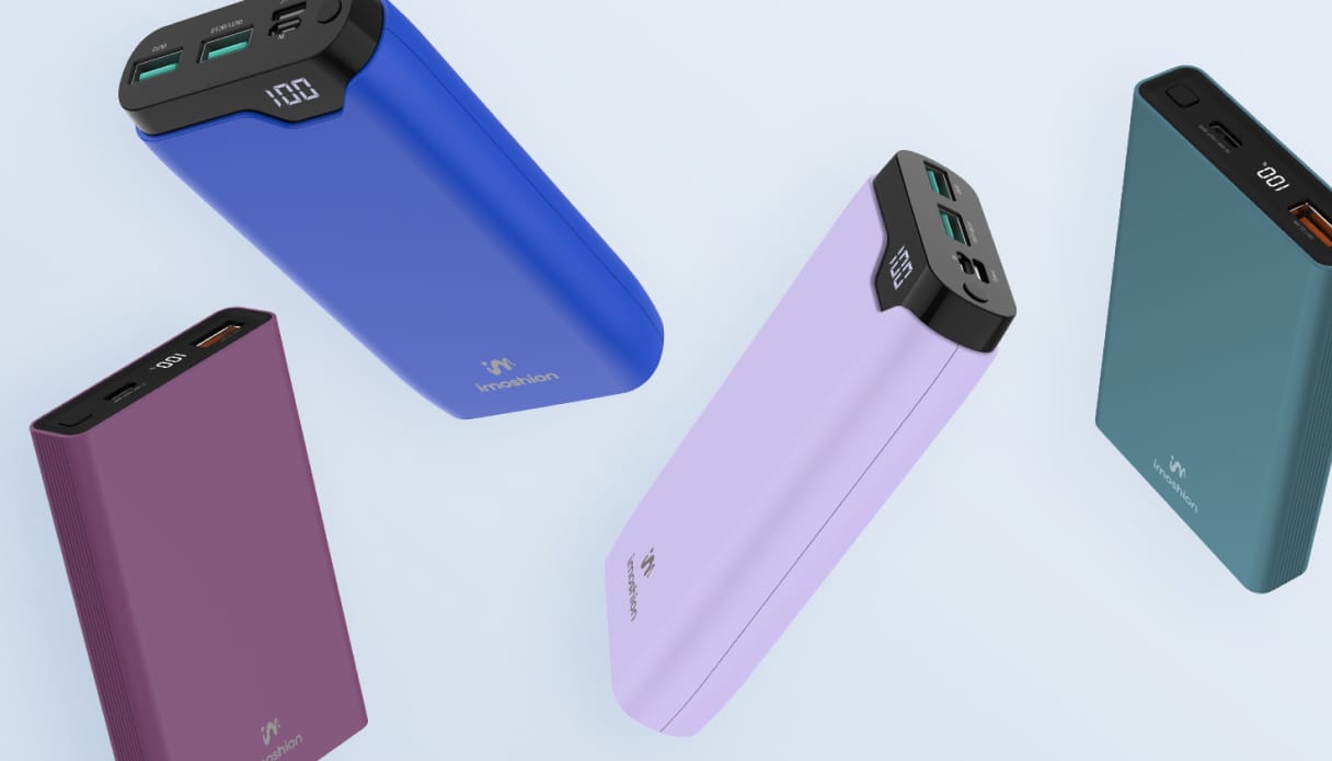 Vier verschiedene, farbenfrohe Powerbanks schweben auf einem hellblauen Hintergrund.
