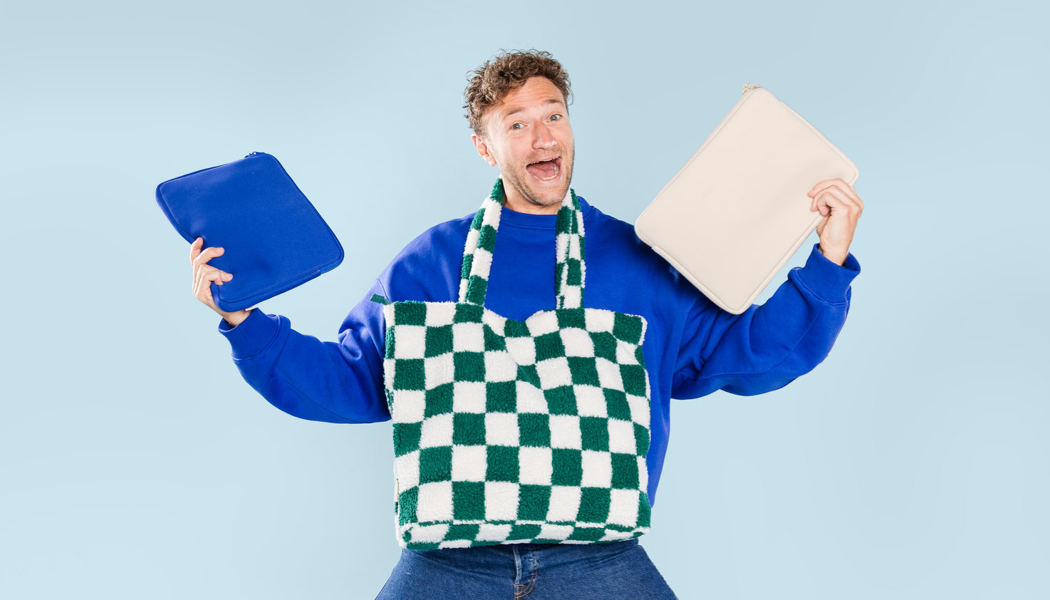Ein Mann mit verschiedenen Laptophüllen in seinen Händen und einer Laptoptasche um den Hals.