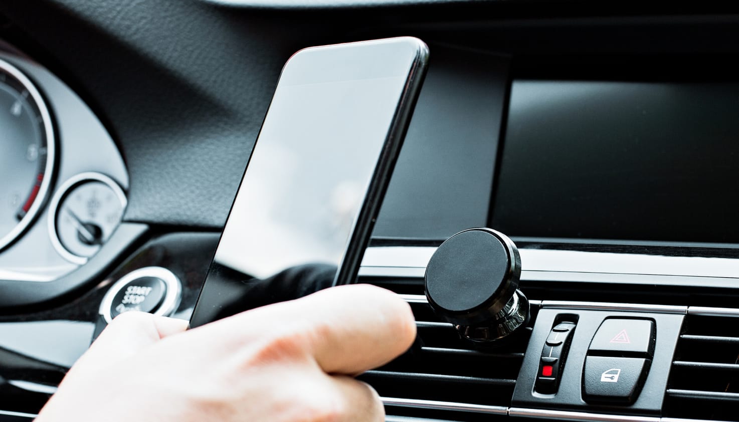 Jemand im Auto hält ein Telefon mit Halterungen.