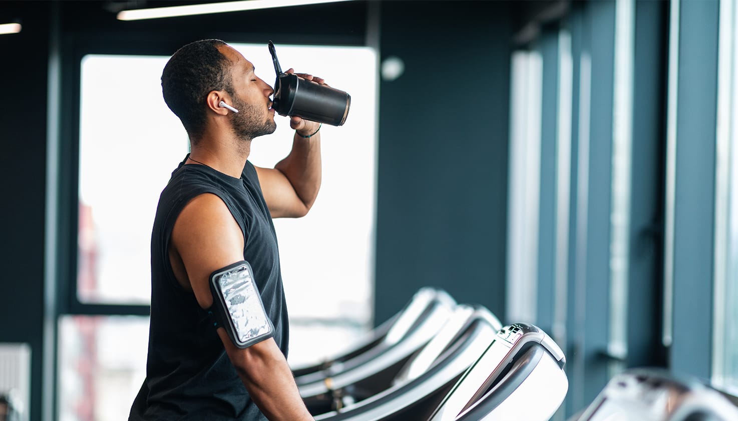 Ein Mann steht auf dem Laufband mit Apple AirPods Pro im Ohr und hört Musik.