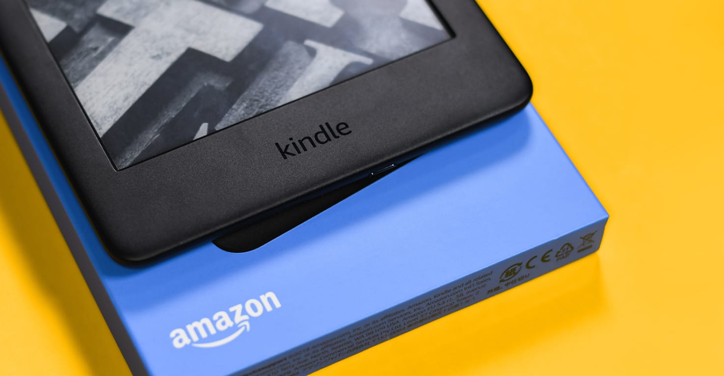 Ein Amazon Kindle und die Verpackung auf einem gelben Hintergrund