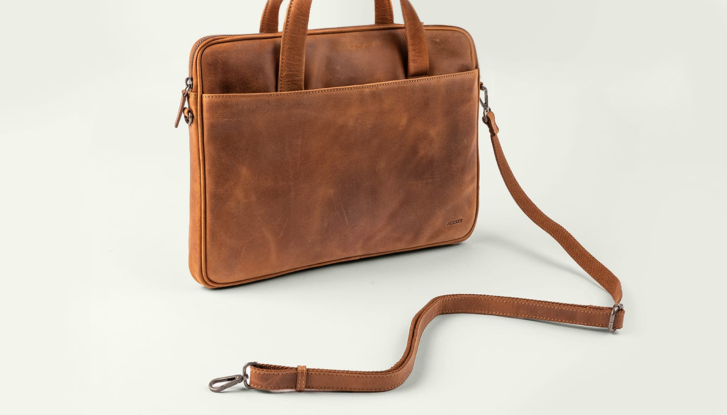 Eine cognacfarbene Laptoptasche mit Schulterriemen.