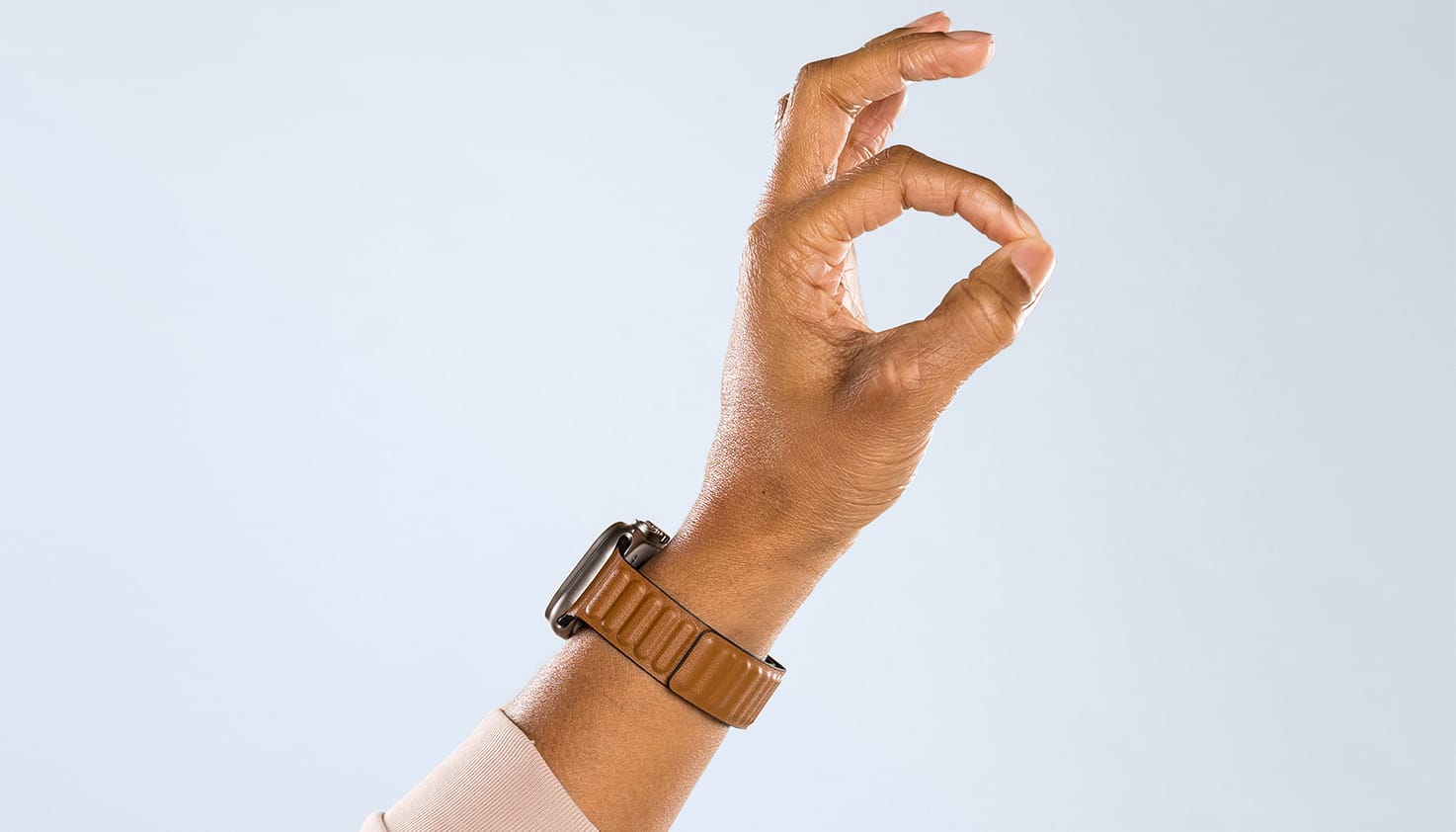 Foto eines Armabschnitts mit Hand. Die Person trägt eine Smartwatch und zeigt das universelle „Okay"-Zeichen.