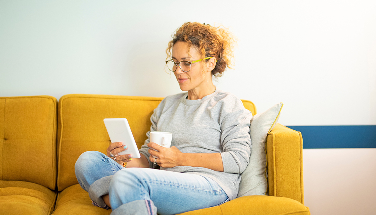 Eine Frau auf dem Sofa liest auf einem E-Reader.